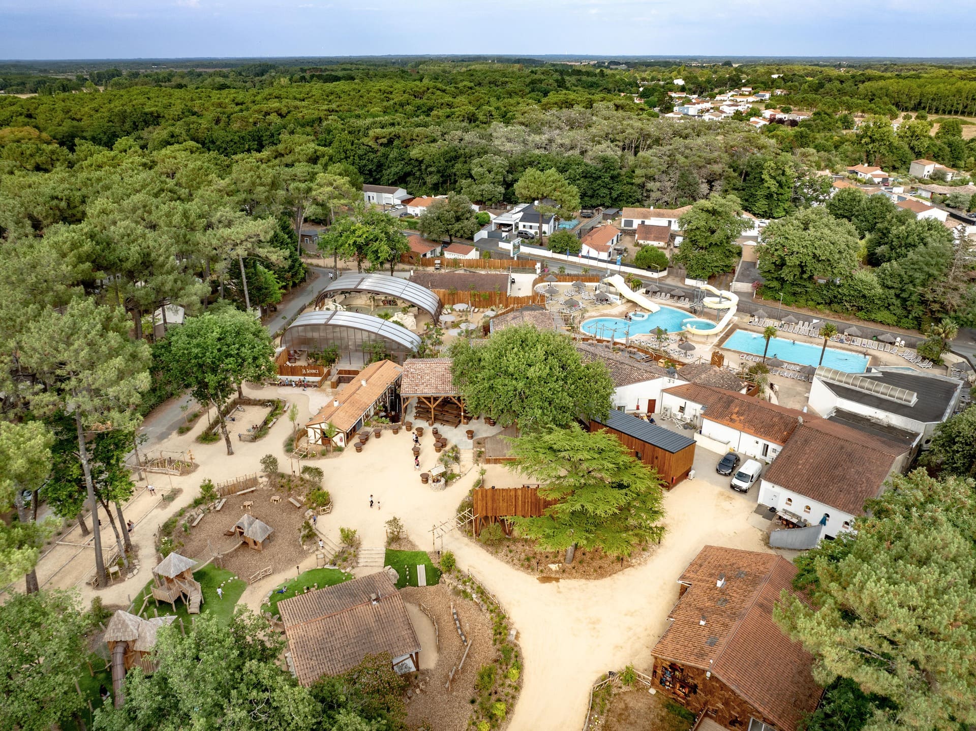 Aerial view of Camping Au Bois des Biches in Saint-Hilaire-de-Riez, nestled in a pine forest and close to the sea, blending nature with a magical, fairy-tale atmosphere.